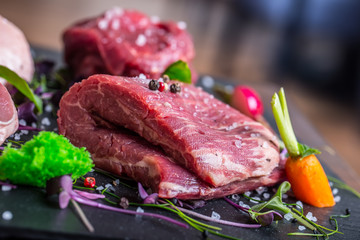Steak.Beef steak.Meat.Portioned meat.Raw fresh meat.Sirloin steak.T-Bone steak. Flank steak. Duck breast. Vegetable decoration. Portioned meat prepared for processing in a restaurant or hotel kitchen.