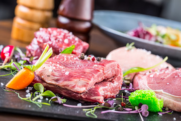Steak.Beef steak.Meat.Portioned meat.Raw fresh meat.Sirloin steak.T-Bone steak. Flank steak. Duck breast. Vegetable decoration. Portioned meat prepared for processing in a restaurant or hotel kitchen.