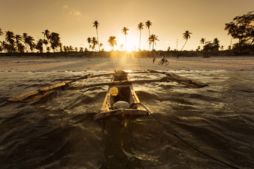 Traditional fishing boat floating on ocean at beautiful sunset i