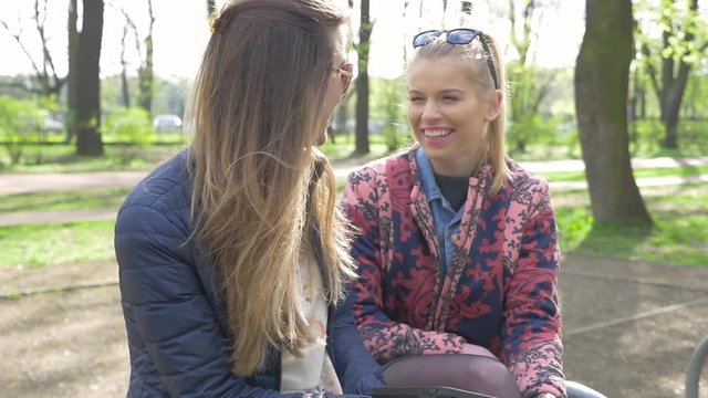 Two girl sitting on the bech in the park and using tablet pc.
