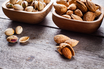 Pistachios and almonds on wooden bowls.