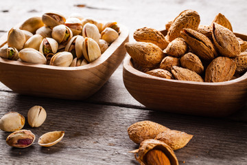 Pistachios and almonds on wooden bowls.