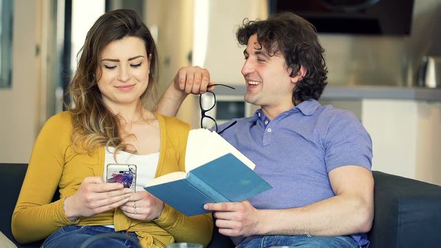Man reading book and his girlfriend using smartphone, steadycam shot
