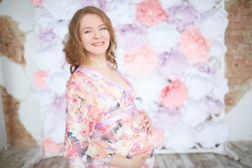 pregnant woman in pink on a background of flowers interior