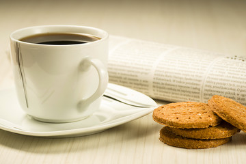 Coffee cup with cookies and newspaper