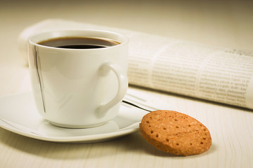 Coffee cup with cookies and newspaper