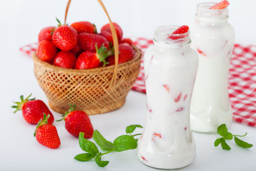 Bottles of strawberry yogurt, with raw strawberries and mint leaves