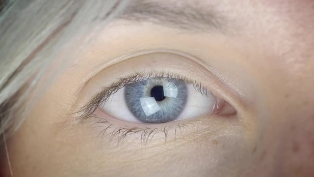 Cinemagraph of a young female blinking eye that opens and closes. The pupil contracts and the iris is blue and green. Loopable motion background - seamless endless infinity video loop.
