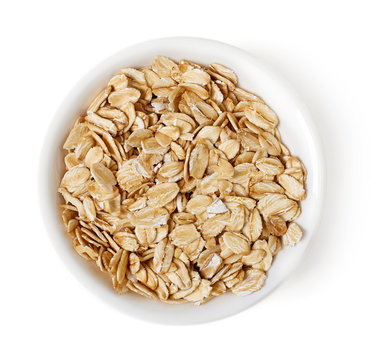 Bowl of oat flakes on white background, top view