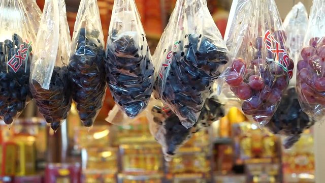fruits seller hanging bag of grapes on hanging stall