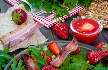 Useful strawberry salad with arugula, nuts and bacon, berry sauce