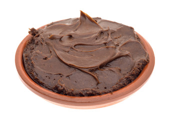 Chocolate fudge frosting in a small bowl on a white background