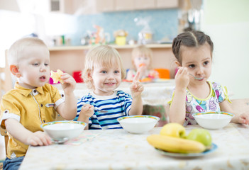 Obraz na płótnie Canvas Funny kids eating in kindergarten