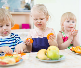 Obraz na płótnie Canvas Funny children eating fruits in kindergarten