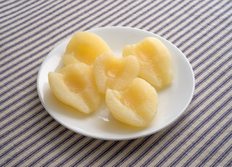 Pears halves on a white plate atop a striped tablecloth