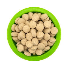 Brewer’s yeast nutritional supplement in a green bowl isolated on a white background top view