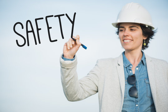 Safety manager. Successful independent engineer smiling woman with safety helmet writing safety on the air. Pioneer woman at work.