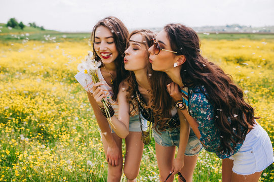 3 beautiful hippie girl in a field of yellow flowers
