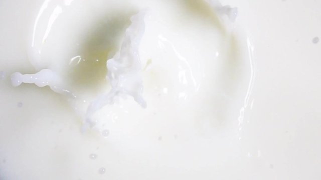 Piece of fresh yellow lemon falling down into fresh white milk with explosive beautiful splash. Shot in slow motion mode on high-speed camera Sony rx 10 ii. 