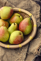 Fresh pears in a wooden basket on a hessian with vintage style