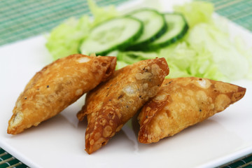 Indian samosas with green lettuce and slices of cucumber on the side, closeup

