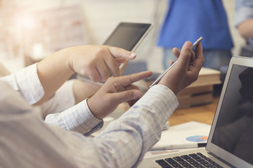 man's hand working with mobile phone, tablet, document and lapto
