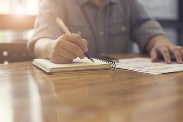 woman's hand writing on notebook with document, selective focus