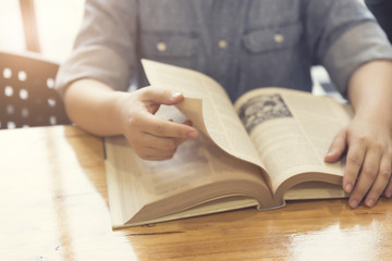 woman's hand reading book on wooden table