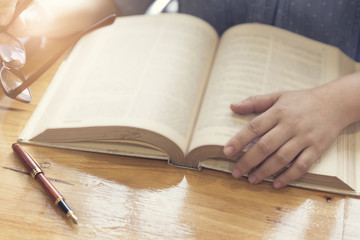 woman's hand reading book on wooden table