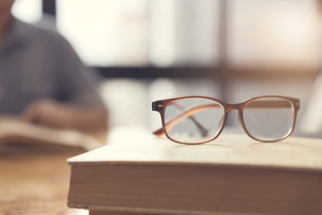 eyeglasses with woman reading book in room