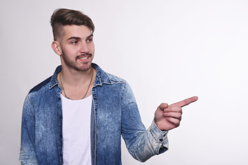 Young man pointing to white background.
