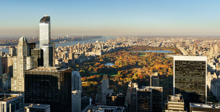 Panoramic aerial view on Central Park in fall colors with Midtown skyscrapers, Upper West Side buildings and the George Washington Bridge in the distance. Manhattan, New York City