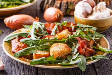 Fresh dandelion salad with fried bacon and garlic croutons.
