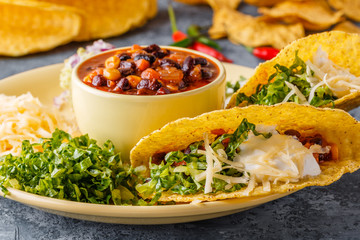 Tacos with chili con carne, salad, cheese and sour cream.