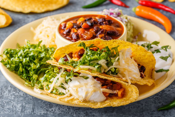 Tacos with chili con carne, salad, cheese and sour cream.