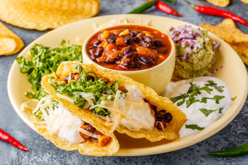 Tacos with chili con carne, salad, cheese and sour cream.