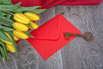 Envelope, rusty key and tulip on a wooden background