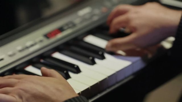 Musician playing keys of synthesizer keyboard – fingers hands close up