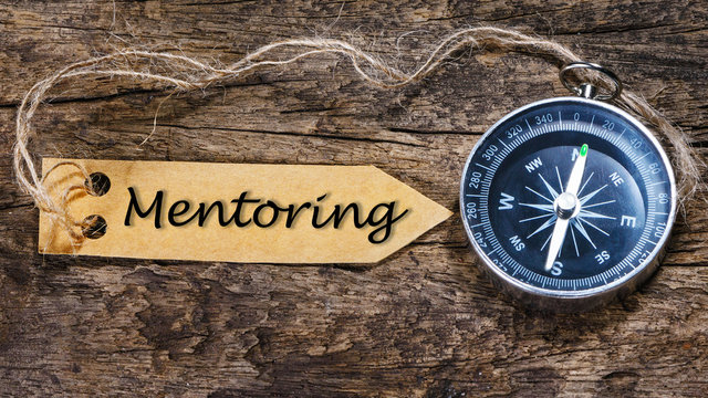MENTORING word - business tips handwriting on label with compass