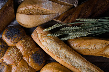 Assortment of baked bread on wooden table background