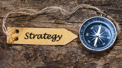 Compass on wood background with strategy written on label tag