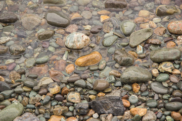 River pebbles of different colors on the river bank in the summe