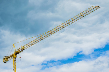Industrial background with yellow construction crane over amazing sky