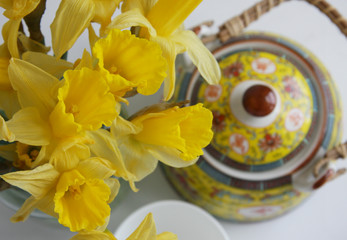 Top view of daffodils, teapot and a cup