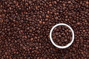 white cup of roasted coffee bean on top of flat lay of brown roa