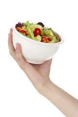 a hand holding a bowl of fresh vegetable salad