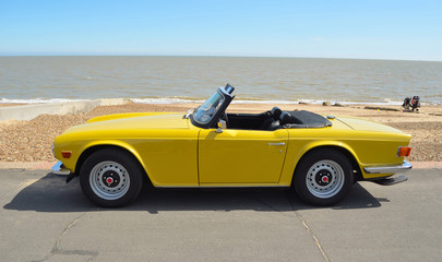 Classic Yellow Triumph TR6 on the seafront at Felixstowe. - obrazy, fototapety, plakaty