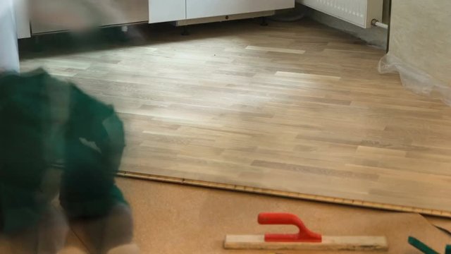 carpenter worker installing wood parquet board during flooring work timelapse