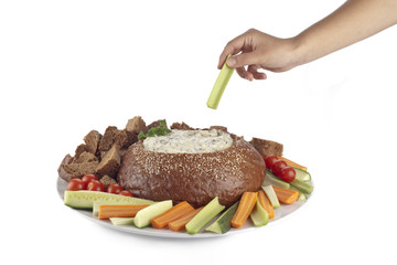 hand holding slice of vegetable with spinach dip on pumpernickel bread