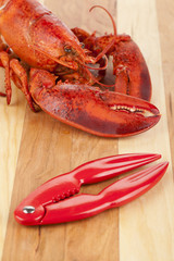 cooked lobster on wooden board with lobster cracker